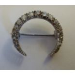 A white metal crescent brooch, set with