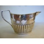 A silver cream jug of oval demi-reeded form with an angular handle John Wilmot Birmingham 1898