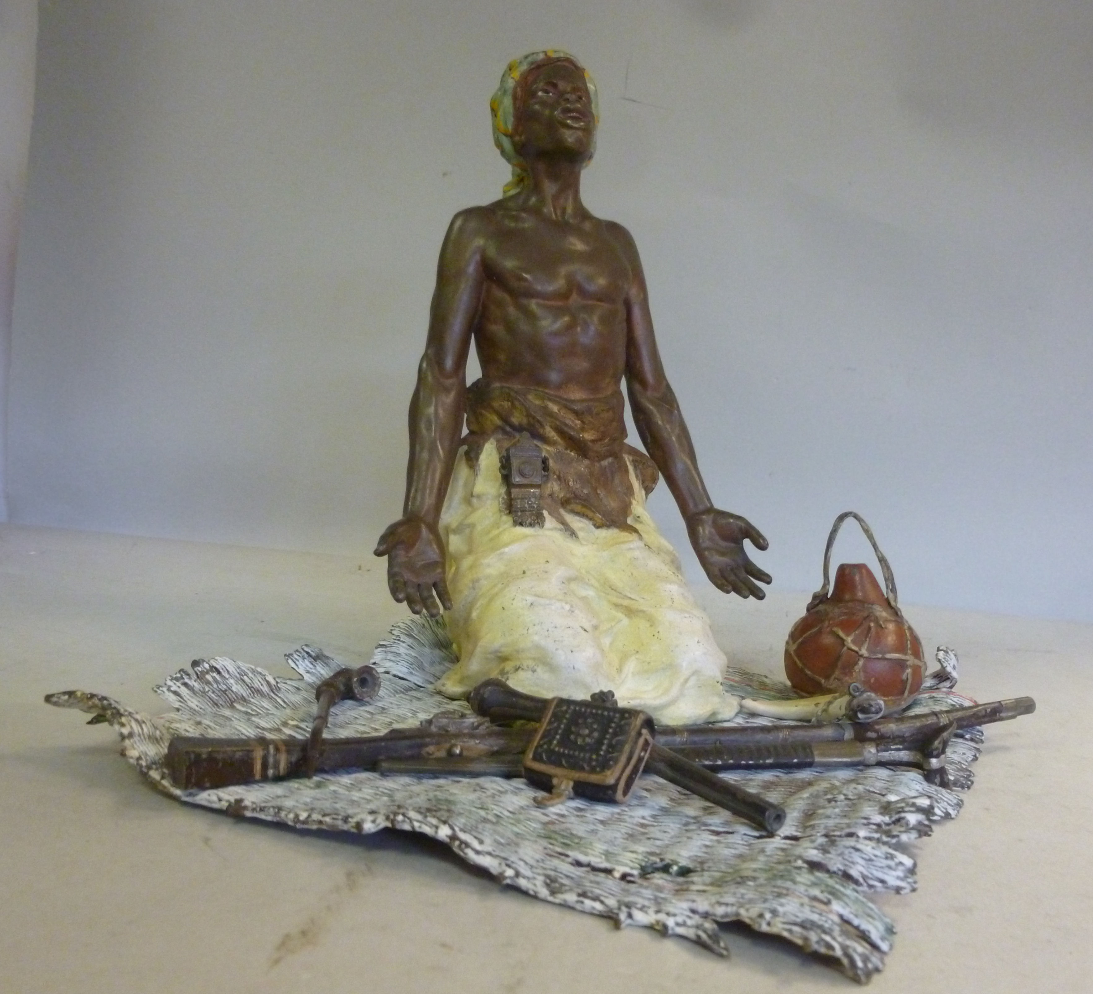 A Geschutzt Bergman cast and cold painted bronze figure, a Nubian kneeling on a rush mat, his arms