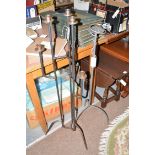 Two tall modern wrought iron candle stands, one in silver, the other in black.