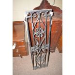 A pair of tall narrow wrought iron panels with hinges.