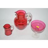 Two Victorian cranberry glass jugs; and a bowl on plain glass stem.