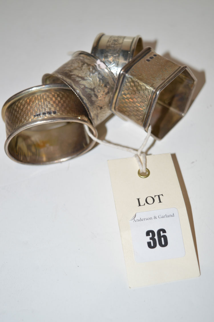 Four silver napkin rings of different designs, one in a case.