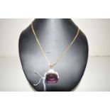A purple glass and 9ct. yellow gold swivel fob, on yellow metal chain stamped '750'.