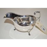 A silver sauce boat, the rim with beaded decoration, acanthus capped scrolling handle,