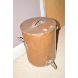 A cylindrical copper container with brass top and two carry handles, the lid also with handle.