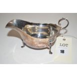A silver sauce boat, the shaped rim with scrolling handle and pad feet.