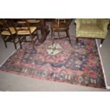 A mid 20th Century rug with Heriz type decoration on claret ground.