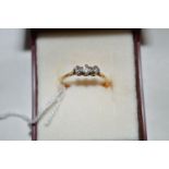 A three stone diamond ring, the brilliant cut diamonds in crown mount above chenier shoulders,