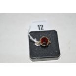 A garnet ring, the oval facet cut garnet four claw set within openwork mount and shoulders, on 9ct.