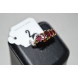 A garnet ring, the five graduated oval facet cut garnets claw set above scrolling shoulders on 9ct.