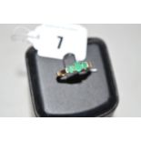 An emerald and diamond ring, the three graduated oval facet cut emeralds each four claw set,