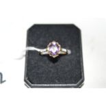 An amethyst and diamond ring, the oval facet cut amethyst four claw set in openwork mount,