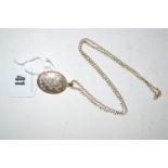 A 9ct. gold oval locket pendant, engraved with floral scrolls, on a curb link 9ct. chain, 6.5grms.