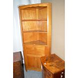 A stained wood corner unit with open shelves above panel door.