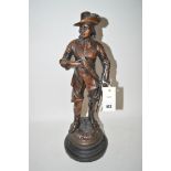 A spelter bronze effect figure of a cavalier standing on a circular plinth base.