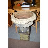 A reconstituted stone garden urn with acanthus leaf decorated rim, standing on a square base.