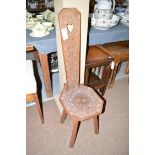 A carved oak spinning stool, with heart-shaped cut-out to back and decorative motifs carved overall,