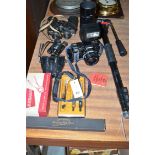A Minolta camera and telephoto lens; a prisma camera stand; three pairs of binoculars;