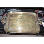 A rectangular Indian brass tray with ornate handles and shaped edge.