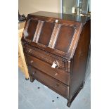 A dark stained oak bureau, the panelled fall-flap enclosing fitted interior,