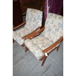 A pair of easy armchairs with exposed open arms, upholstered in patterned material.