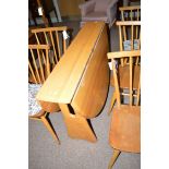 A light stained Ercol drop-leaf dining table.