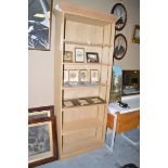 A tall modern oak bookcase with adjustable shelves.