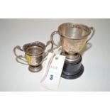 Two silver trophy cups, one on ebonised stand.