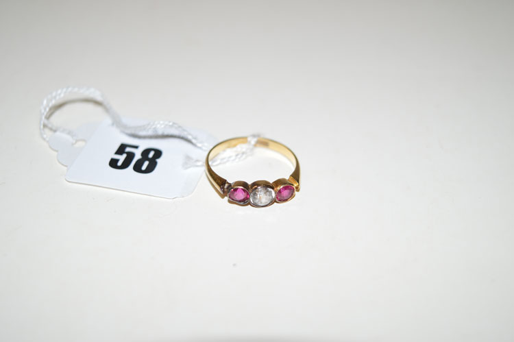 A white and red stone ring, the central white stone flanked by two red stones, all in collet mounts,