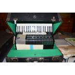 A Hohner electrobox piano accordion in case.