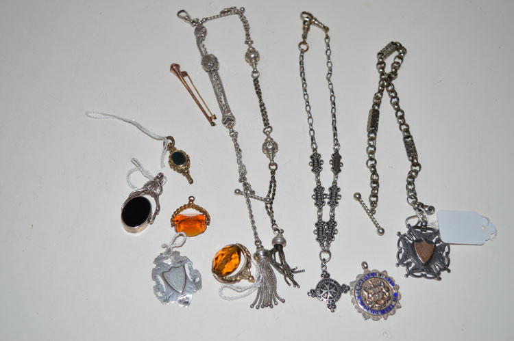 A quantity of silver watch chains; fobs; a gilt metal watch key; an onyx set swivel fob;