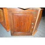 An antique oak single door hanging corner cupboard.