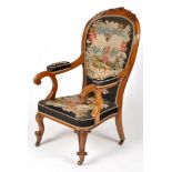 A Victorian carved walnut open arm easy chair, the curved cresting rail carved with floral designs,