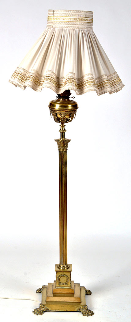 A Victorian brass standard lamp, fitted cream coloured shade, oil reservoir below,