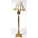 A Victorian brass standard lamp, fitted cream coloured shade, oil reservoir below,