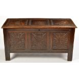 An 18th Century oak blanket box, the hinged top above carved foliate panel front,