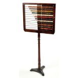 A mahogany framed abacus on stand, with twelve rows of coloured wood counting beads, stamped "LCC L.