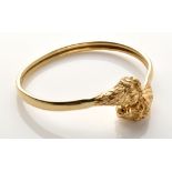 A yellow metal bangle, the terminals decorated with lion masks on a double tubular bangle,