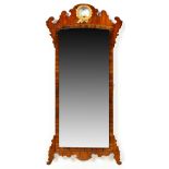 A George III style walnut wall mirror, the shaped frame with gilt wreath pattern pediment,