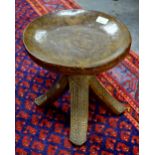 An African Yarouba carved wood stool having a dished circular seat raised on four outswept legs with