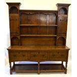 An Arts & Crafts light oak high dresser, the top centered by open shelves flanked by upright