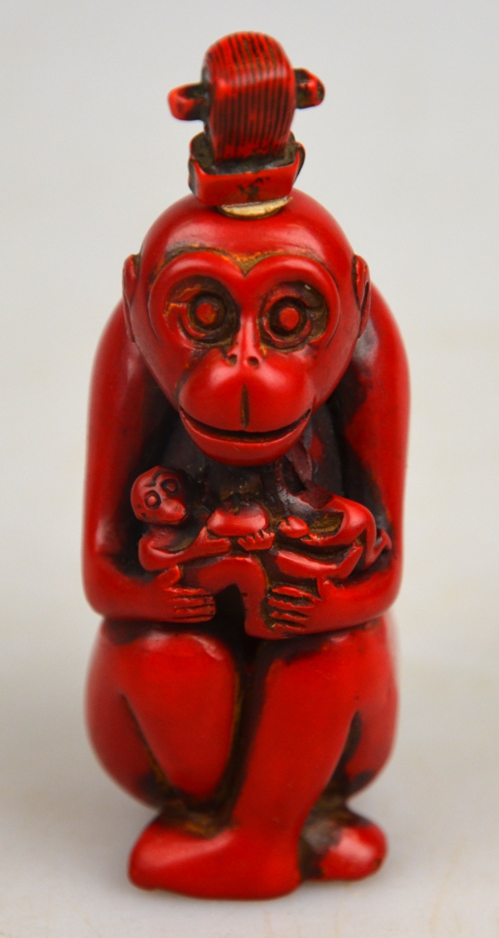 A Chinese red coloured hardstone snuff bottle and stopper in the form of a monkey, 8.5 cm One