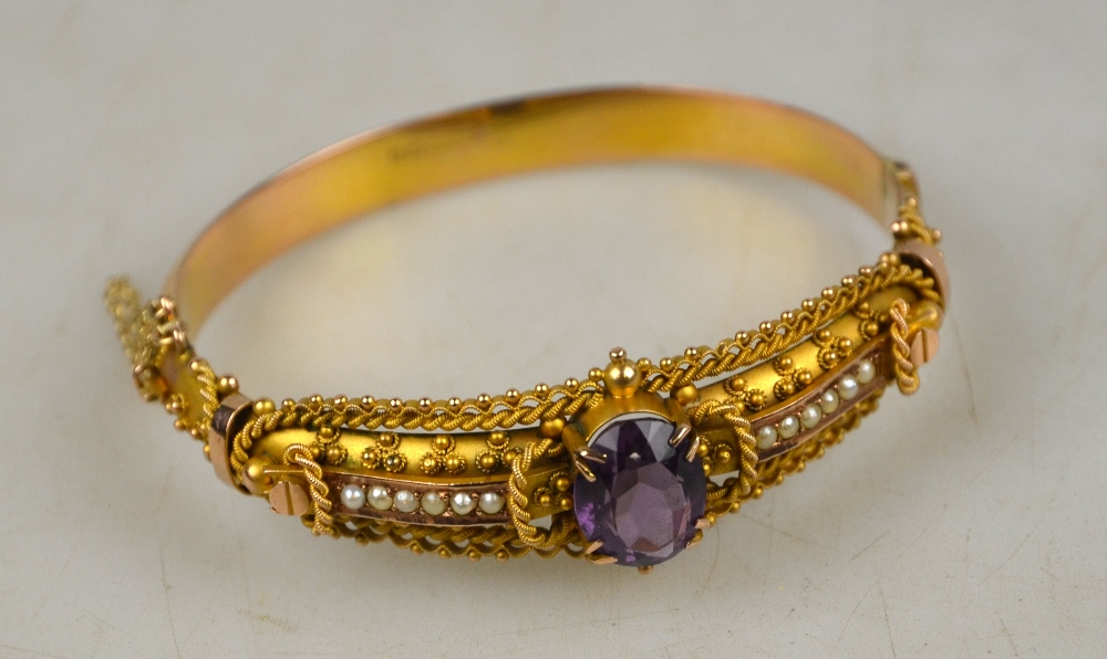 An Etruscan style hinged bangle having bloomed gold front section set oval facetted amethyst and