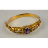 An Etruscan style hinged bangle having bloomed gold front section set oval facetted amethyst and