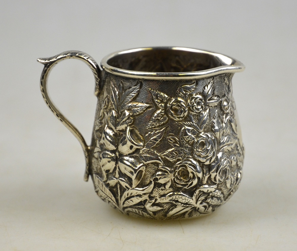 An American Baltimore 11 oz silver cream jug, richly chased and embossed with floral decoration,