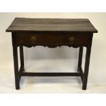 A 17th century oak joint table, the three plank top over a drawer within a shaped frieze, raised