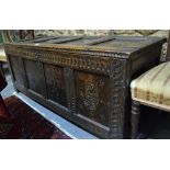 An 18th century oak panelled coffer, the hinged top over a carved frieze and four later carved