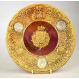 An ornate Continental brass plate, set with Spanish silver coins and a central coat of arms on