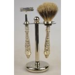 A modern 'badger' shaving brush and razor with antique silver handles, on chrome stand